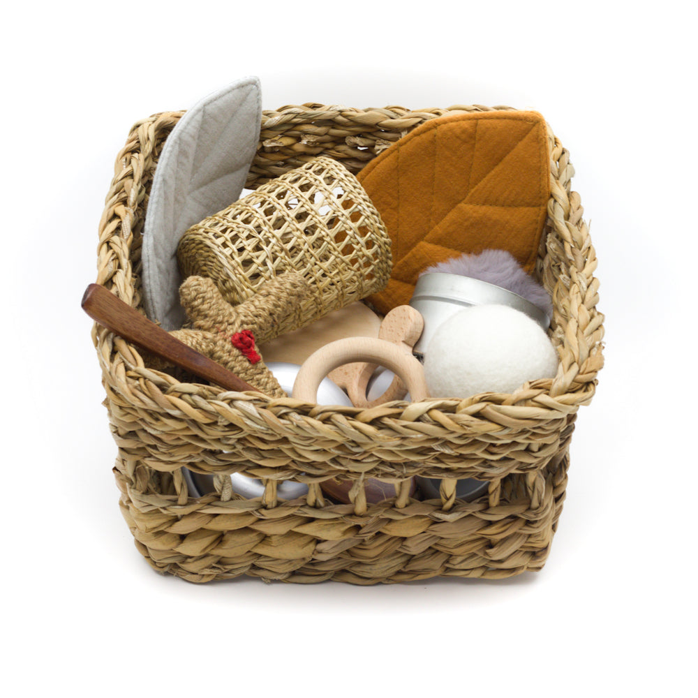 A woven natural basket filled with open-ended baby and toddler play toys