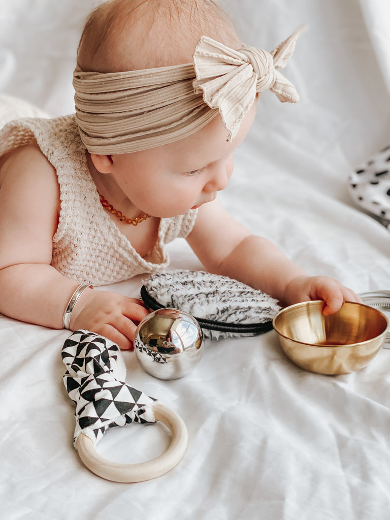 Baby exploring natural heuristic play set on a playmat. Eco-friendly sensory toys designed to support brain development and motor skills.